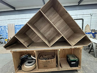 A large, unfinished wooden shelf with diagonal shelves