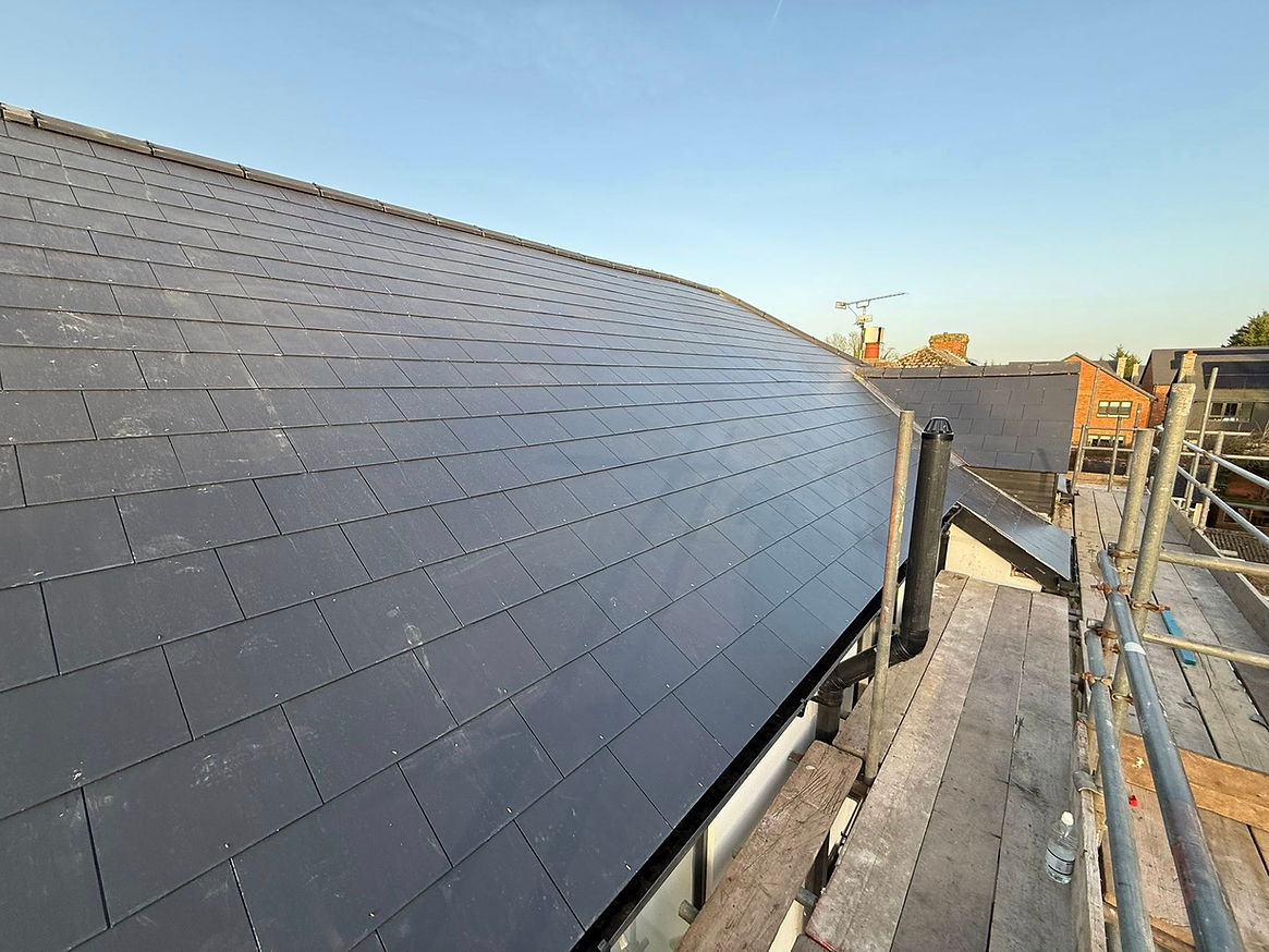 A roof featuring a combination of black slate tiles and metal roofing materials