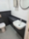 Modern bathroom with white walls, a wall-mounted sink on a black counter