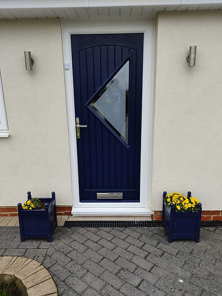 A navy blue front door with a triangular frosted window, flanked by two wall lights