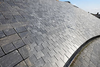 Roof with overlapping gray slate tiles forming a geometric pattern