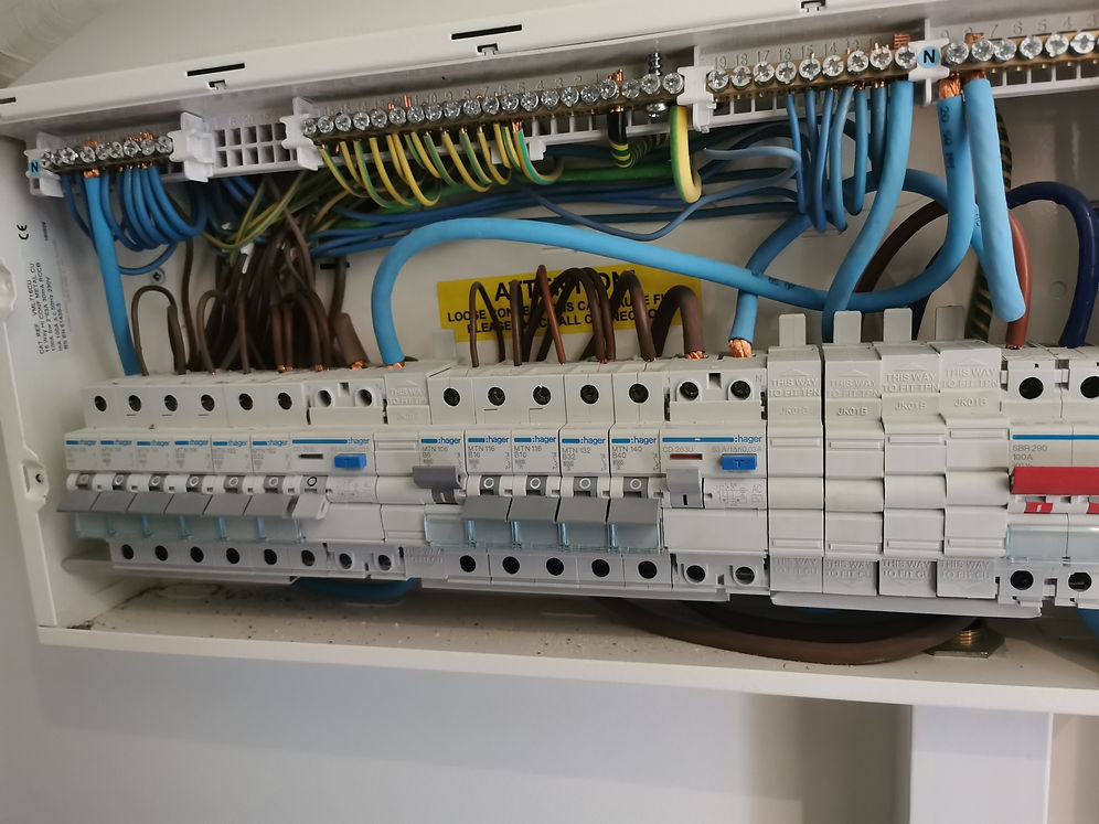Electrical panel with multiple circuit breakers, surrounded by tangled blue and brown wires