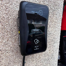 Black EV charger mounted on a textured exterior wall
