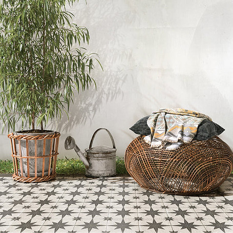 Potted plant and wicker ottoman with cushions on star-patterned tile floor