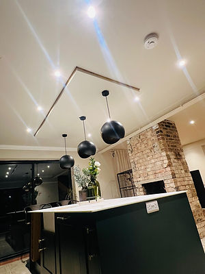 Modern kitchen with exposed brick wall and sleek island. Black pendant lights hang from the ceiling