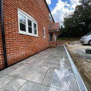 A brick house with modern grey stone paving and white-framed windows