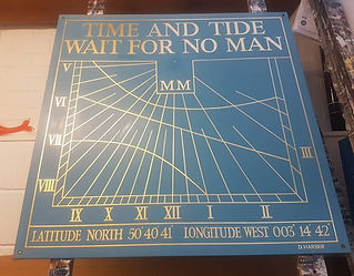 A blue sundial panel with gold lines and text. It reads "Time and tide wait for no man