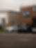 Side profile view of a black BMW car parked in front of a brick building wall outside a garage
