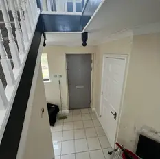 View of a tiled foyer with a white staircase on the left, a gray door straight ahead