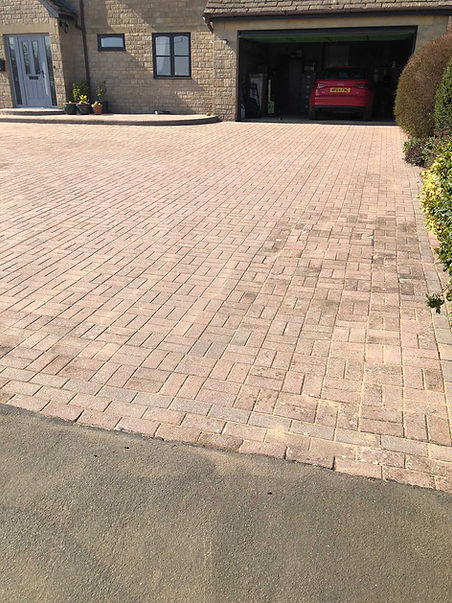 Long block paved driveway with distinct decorative borders stretching alongside a garden border