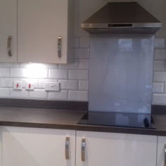 Kitchen stove area featuring white subway tile splashback and a sleek extractor hood