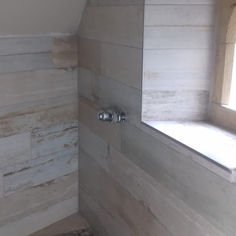 Light wood-effect tiled bathroom walls featuring an alcove window shelf