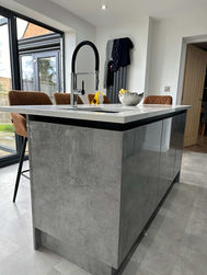 Modern kitchen with concrete island, black stools, and natural light