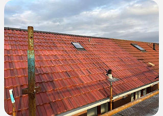 Red-tiled roof with a single skylight window under a cloudy sky