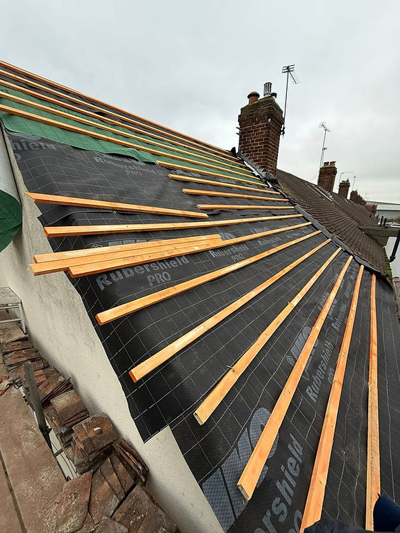 Roofing workers repairing a residential roof in Leicester, with tools and materials visible on the site
