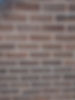 A close-up of a brown brick wall with uniform horizontal rows