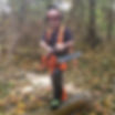 Man in safety gear with a chainsaw, standing on a log