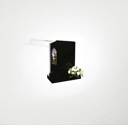 A black headstone with a colorful stained glass insert depicting an angel stands against a white background