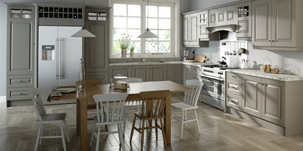 Farmhouse-style kitchen with muted taupe-grey cabinets, speckled granite countertops, and a wooden dining table