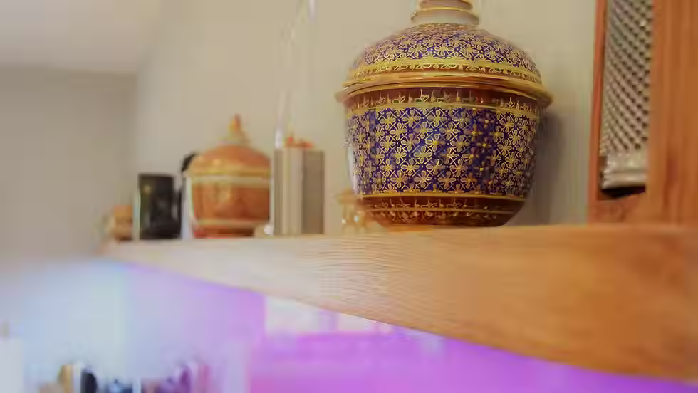 Close-up of an ornate, blue and gold ceramic jar on a wooden shelf