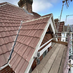 A tiled roof and chimney on a house with blue sky