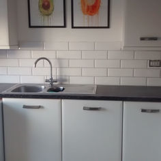 Kitchen sink and countertop backed by bevelled white subway tiles
