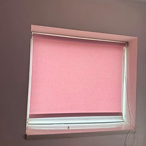 Pink motorised roller blind installed on an interior window frame