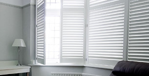Sleek full height window shutters custom fitted in a brightly lit interior space