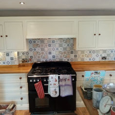 Black range cooker with a colorful, patterned mosaic tile splashback and white cabinets