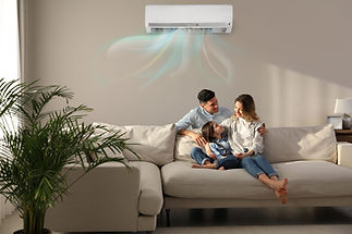 Family of three relaxing on a beige sofa under an air conditioner with visible airflow