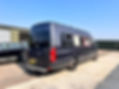 Black camper van parked on sunny lot near green building
