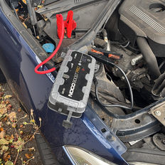 Close-up of portable jump starter connected to a car battery