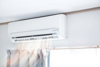 Wall-mounted air conditioner above a window with closed curtains