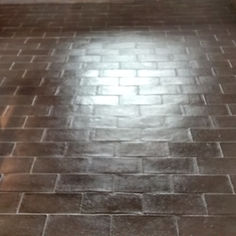 Dark brown ceramic brick-style tiles on a floor reflecting light