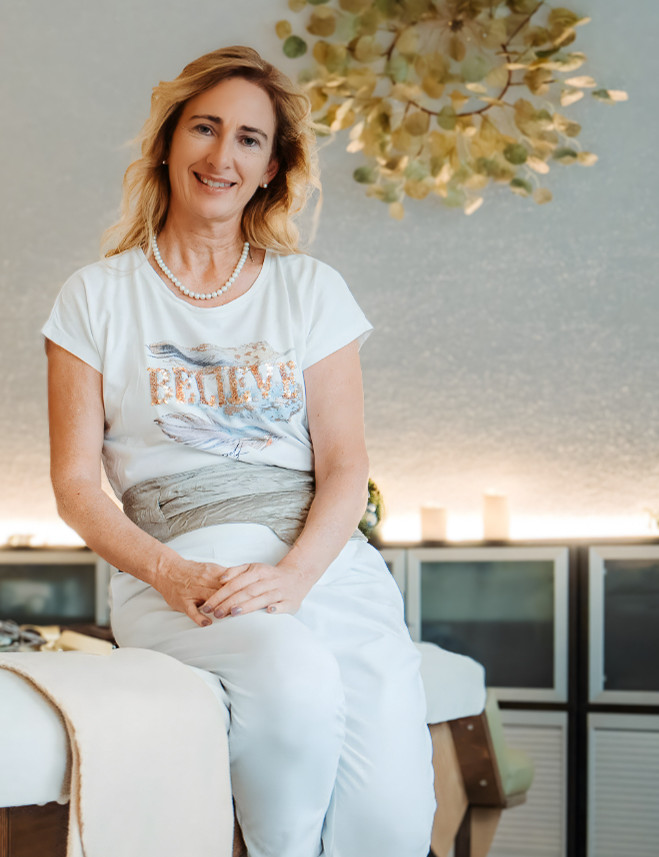 Lächelnde Frau in Praxis auf Behandlungsliege.