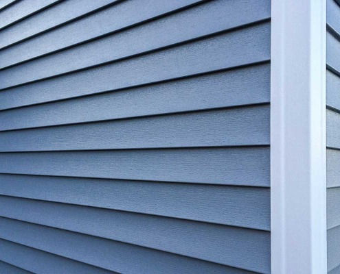 Close-up of blue siding texture with white trim and Siding Replacement.