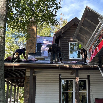 Roofers working on a house roof with a chimney and ladder Roofing Contractor