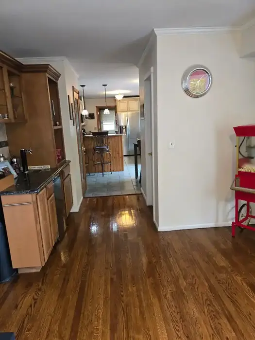 Cleaner dusting high kitchen cabinet using ladder during professional deep cleaning service