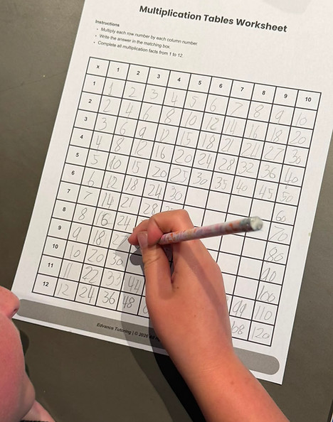 A friendly tutor helping a high school student with their math homework at a desk