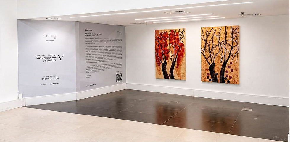 Parede branca exibe dois quadros de árvores com folhas vermelhas e fundo alaranjado. Placa com texto de exposição ao lado. Ambiente moderno.