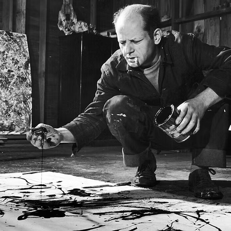 Jackson Pollock agachado no ateliê, aplicando tinta diretamente sobre a tela colocada no chão, gesto característico da action painting, registro do processo corporal e performativo de sua pintura.