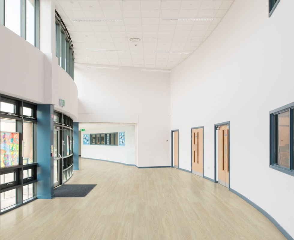 Lichte schoolgang met grote ramen en houten vloer