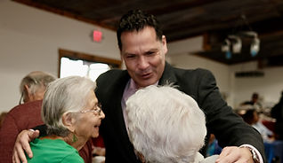 Justin Rodriguez hugging two older women at a community event