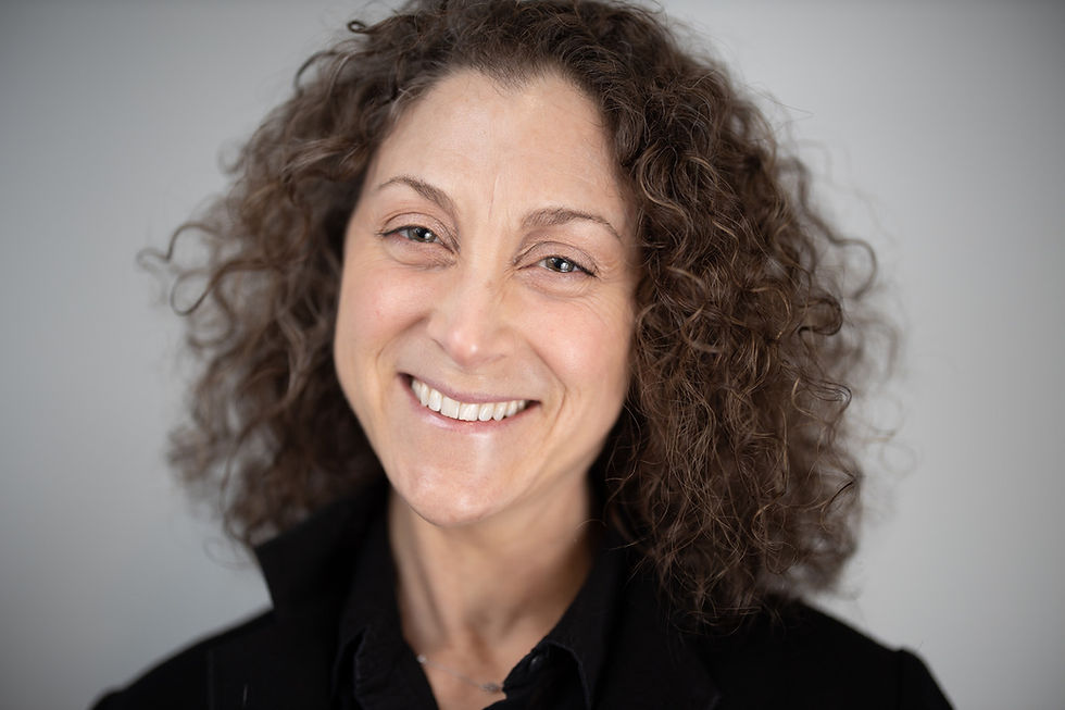 Rochelle Tractenberg in a black collared shirt with a grey background.