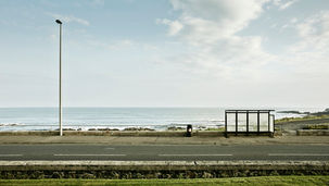 Een bushalte langs de kust bij helder ochtendlicht; het eerste moment van een metamorfose in Noord-Ierland. Fine art fotografie van Leon Bouwman. | A bus stop along the coast in clear morning light; the first moment of a metamorphosis in Northern Ireland. Fine art photography by Leon Bouwman.