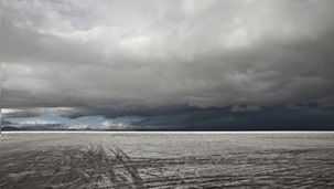 Een verstilde, witte zoutvlakte onder een zware, donkere wolkenlucht op de afgelegen Bonneville Salt Flats, USA. Fine art fotografie van Leon Bouwman, voor serie Somewhere. | A silent, white salt flat under a heavy, dark cloudy sky on the remote Bonneville Salt Flats, USA. Fine art photography by Leon Bouwman, for series Somewhere.
