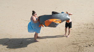Strandbezoekers in Engeland die worstelen met een windscherm op het strand van St Ives, Cornwall. Fine art fotografie van Leon Bouwman. | Beach visitors in England struggling with a windbreak on the beach of St Ives, Cornwall. Fine art photography by Leon Bouwman.