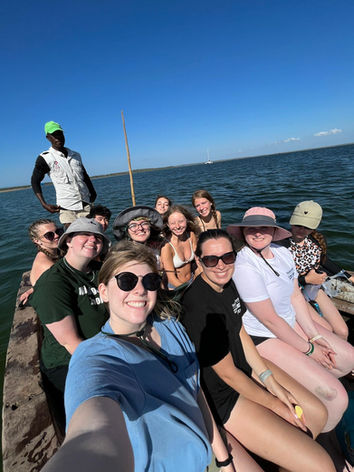 A group of people sit on a wooden boat steered by a local fisherman