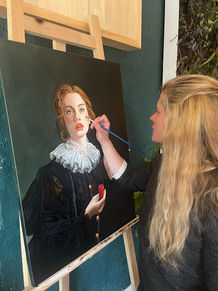 Portrait d’Alice Drapanaski peignant une jeune femme en costume d’époque sur une toile, dans son atelier.