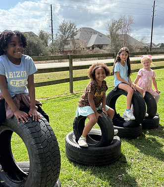 Students at Extraordinary Adventures Academy enjoying outdoor play and teamwork on tire structures in Katy, Texas